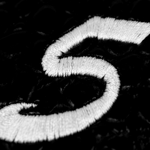 Close-up of embroidered number 5 on a textured black background.