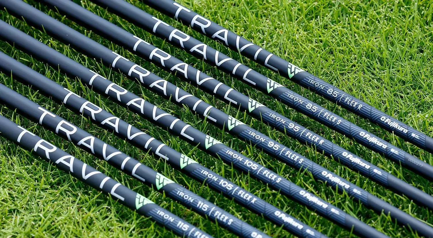 Fujikura Travil 115 iron shafts stacked on grass, showcasing advanced composite technology for performance.