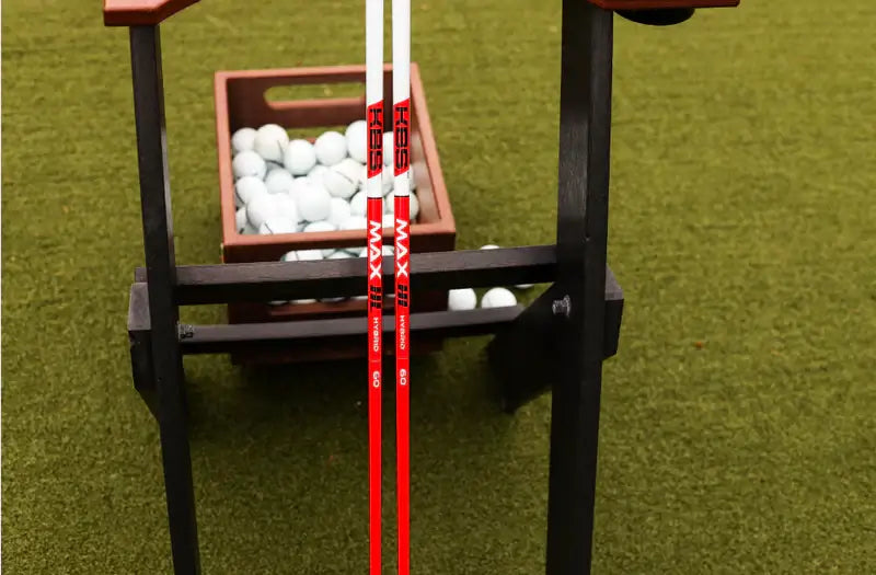 KBS MAX HL Hybrid shafts displayed next to a basket of golf balls on a green turf surface.