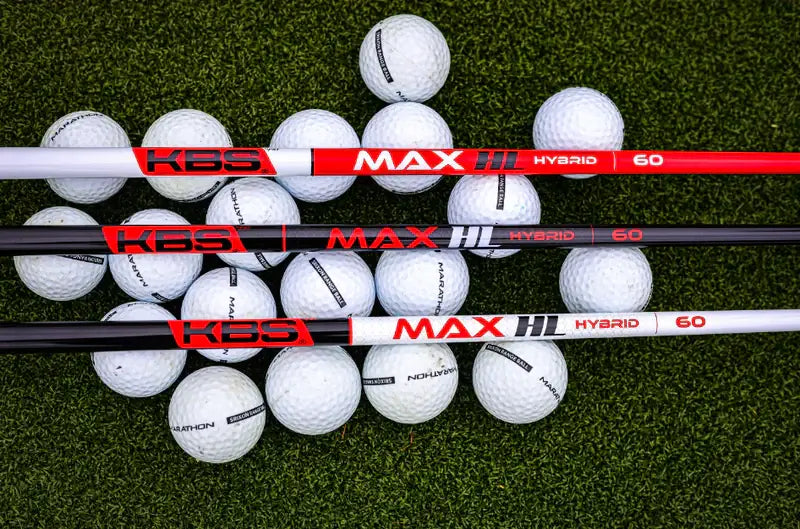 KBS MAX HL Hybrid Shafts positioned on a bed of golf balls, showcasing premium graphite technology for improved swing speed.