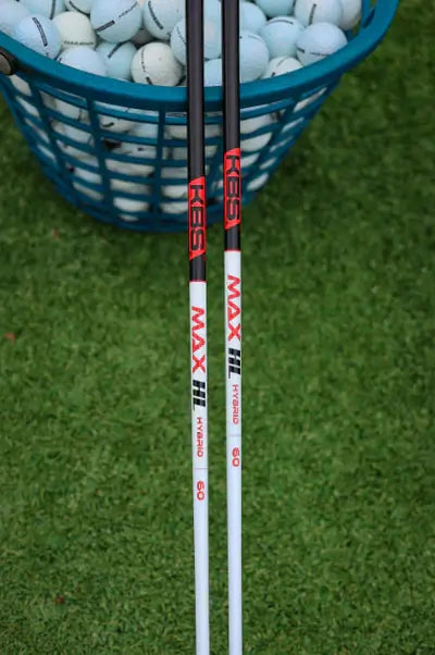 KBS MAX HL Hybrid Shafts placed beside a basket of golf balls on a green turf.