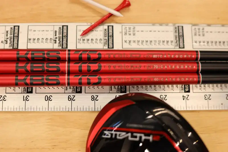 KBS TD Driver/Wood shafts on a table with a golf club head, showcasing performance-driven design and technology.