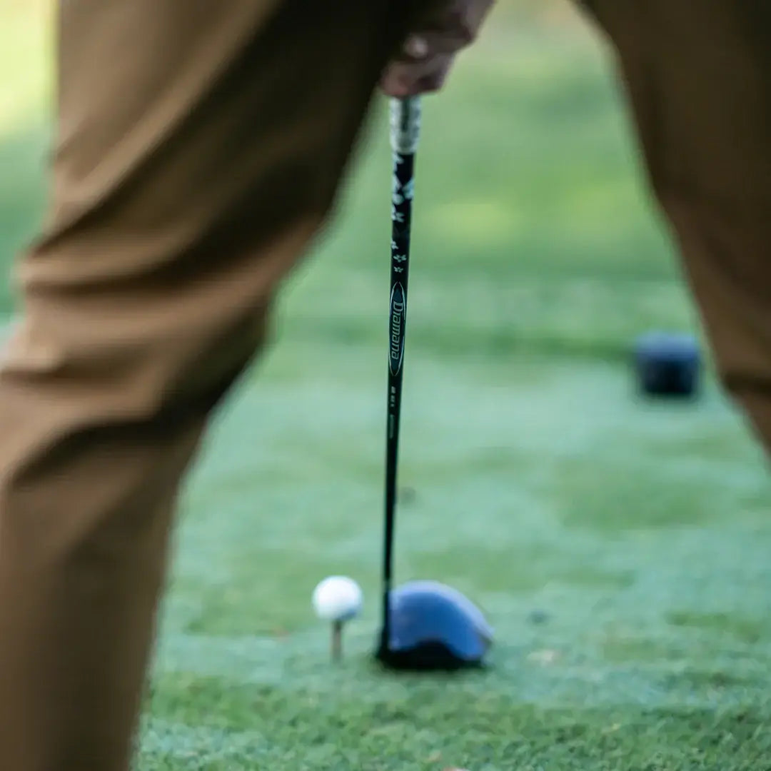 Mitsubishi Diamana BB Blueboard wood shaft poised over a golf ball on a tee, ready for a swing.