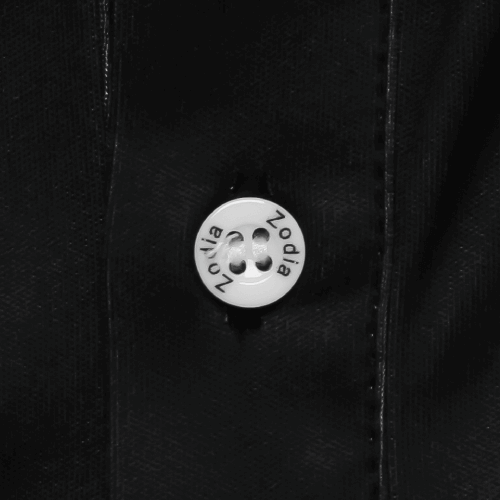 Close-up of button on Zodia Splash Polo Shirt showcasing logo detail on chic monotone fabric.