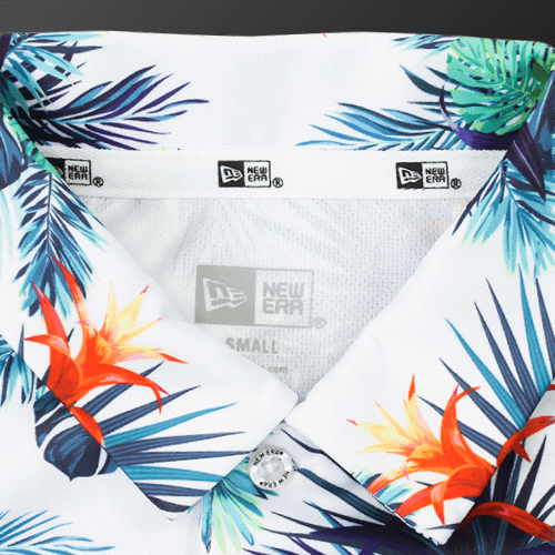 Close-up of the collar and label of a tropical botanical polo shirt featuring vibrant floral patterns.