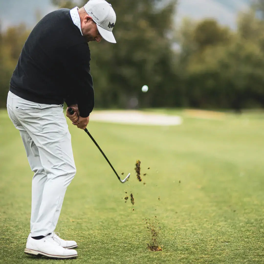 Golfer striking a shot on the course, showcasing the precision and performance of Mitsubishi MMT Taper Iron Shafts.