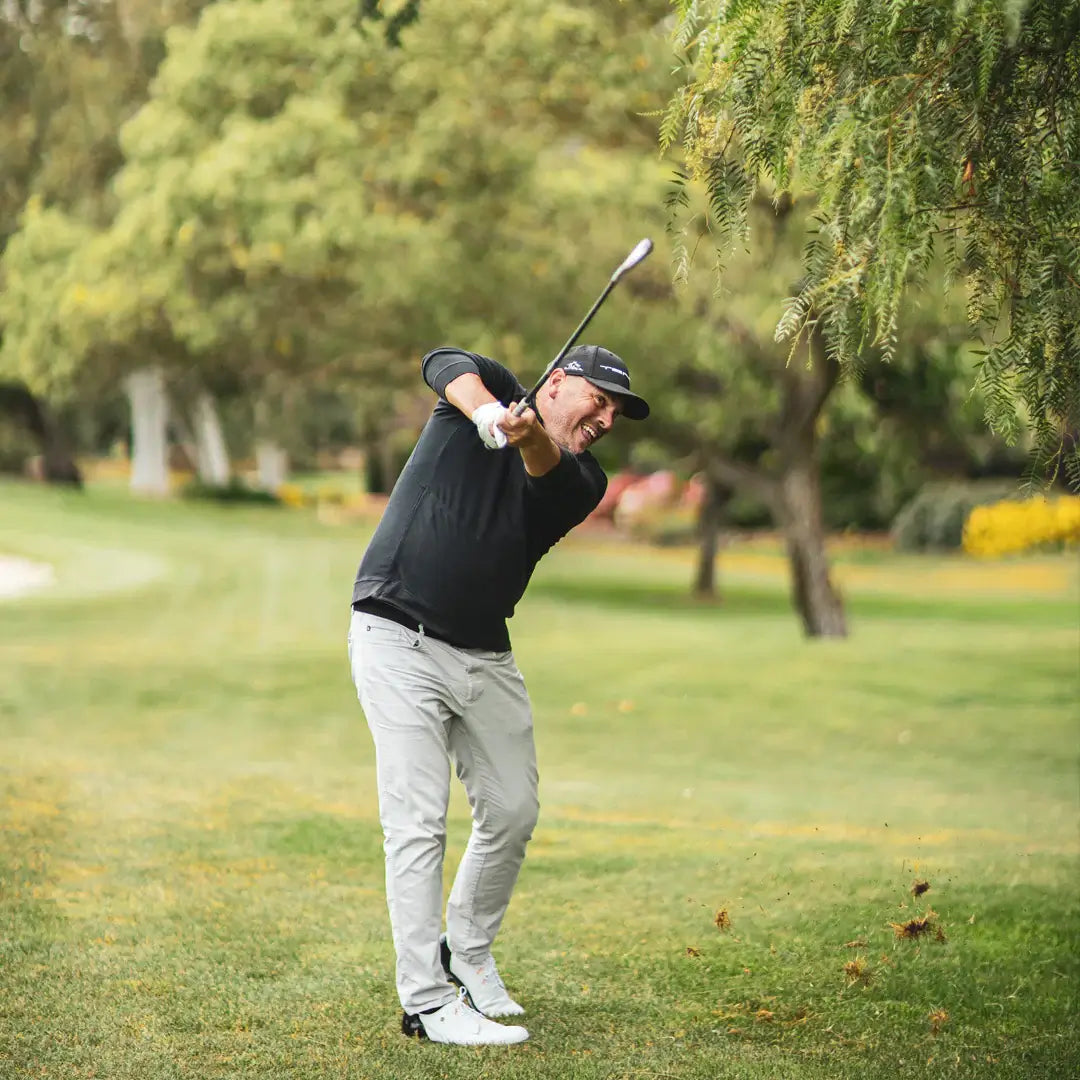 Golfer executing a swing on the course, showcasing precision and technique in a green landscape.