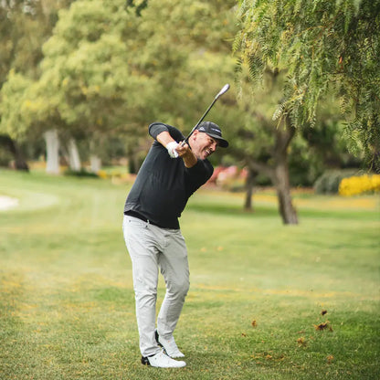 Golfer executing a swing on the course, showcasing precision and technique in a green landscape.