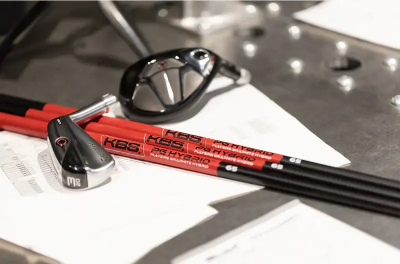 KBS Players Graphite Hybrid shafts showcasing improved launch and spin, with a golf club on a work surface.