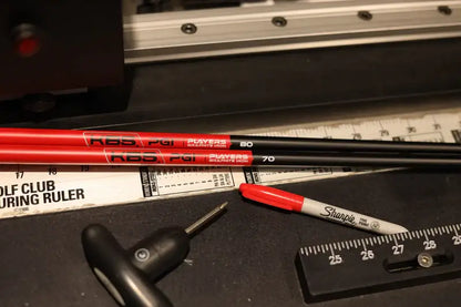 KBS PGI graphite shafts in black and red resting on a golf club ruler, showcasing performance specifications.
