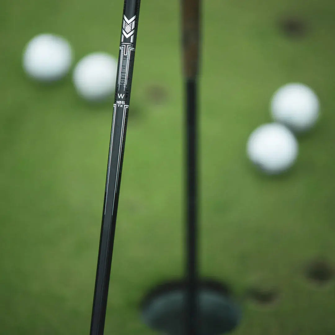 Mitsubishi MMT Scoring Wedge close-up, showcasing Metal Mesh Technology shaft with golf balls in the background.