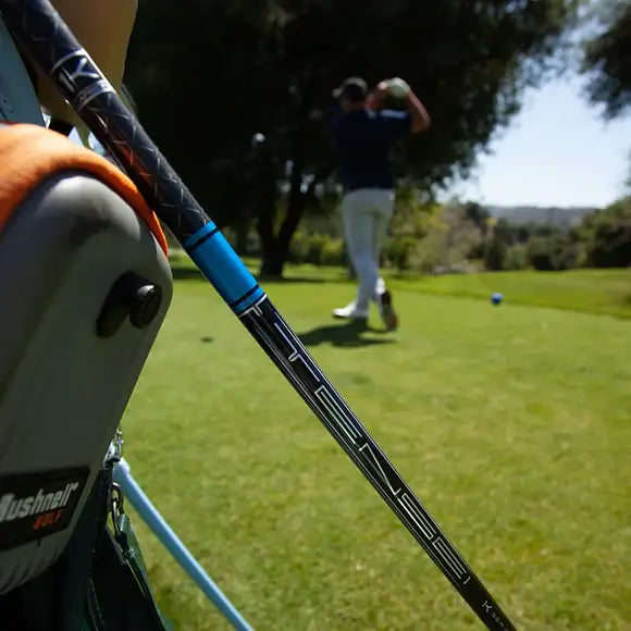 Mitsubishi TENSEI 1K Pro Blue wood shaft in focus with golfer teeing off in the background on a sunny golf course.
