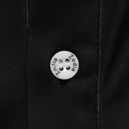 Close-up of button on Zodia Splash Polo Shirt showcasing logo detail on chic monotone fabric.