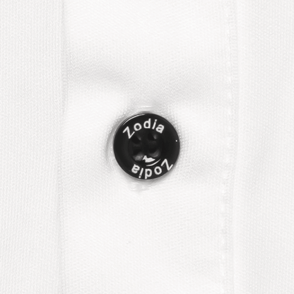Close-up of Zodia logo button on a white polo shirt, showcasing quality and stylish design details.