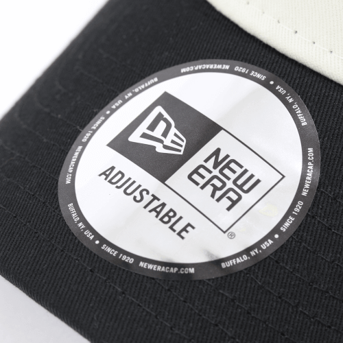 Close-up of New Era adjustable cap tag featuring logo and text on a two-tone mesh cap.