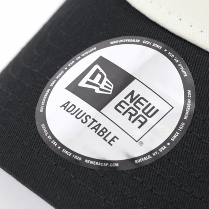 Close-up of New Era adjustable cap tag featuring logo and text on a two-tone mesh cap.