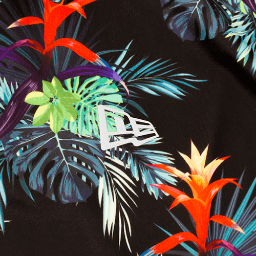 Close-up of Zodia Botanical Polo Shirt featuring vibrant floral pattern and reflective logo detail on black fabric.