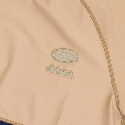 Close-up of the Zodia muta mock neck shirt showing the stylish logo on soft beige fabric.